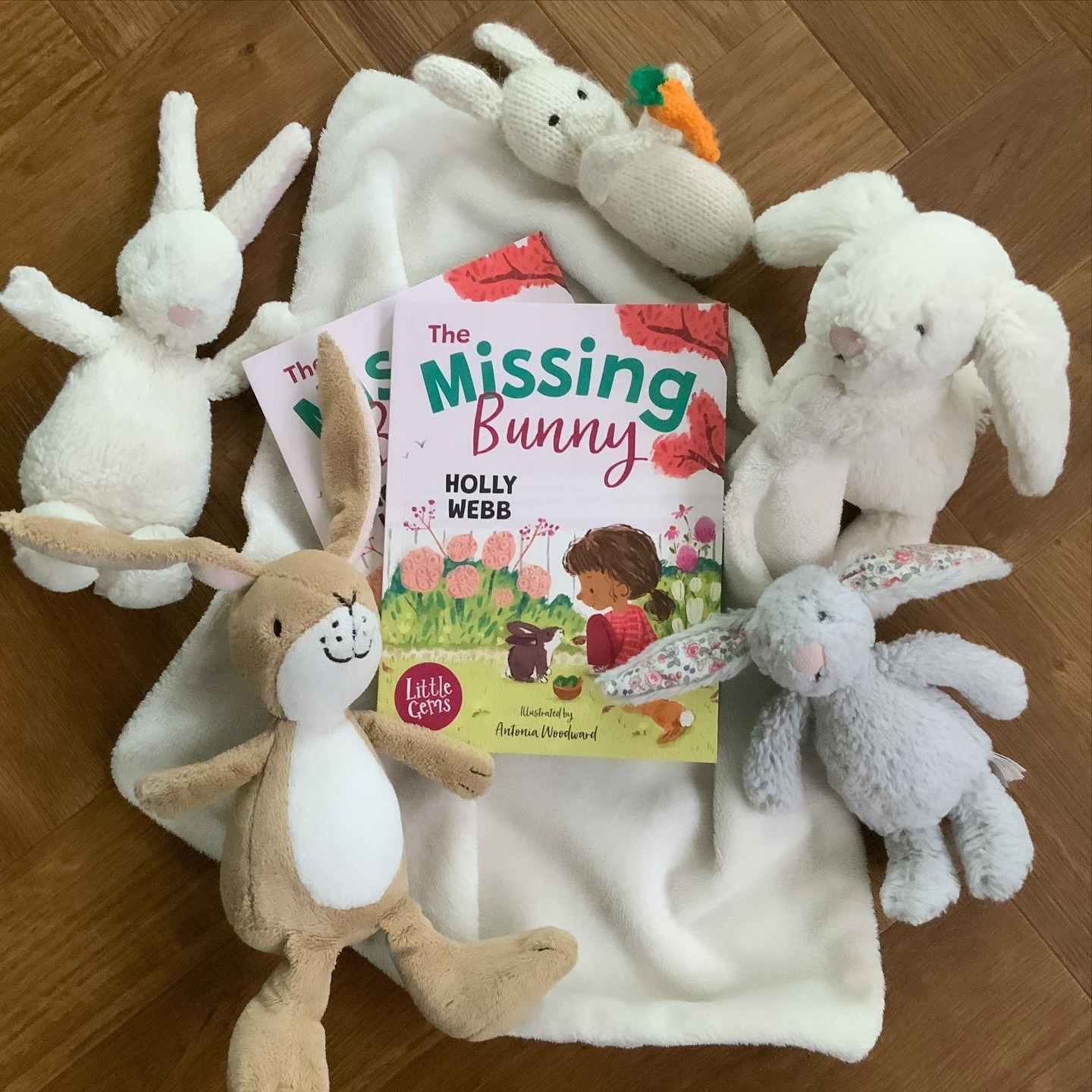 Flat lay photo of two copies of the Missing Bunny by Holly Webb and Antonia Woodward surrounded by soft toy bunnies
